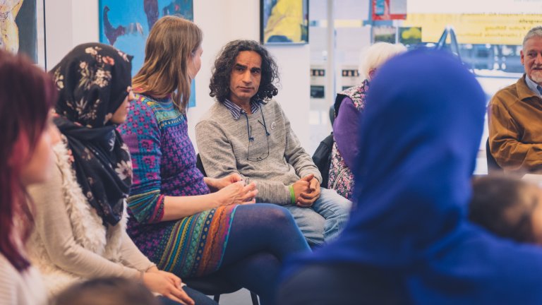 Andere Migranten besuchen Salam Ahmad in seiner Ausstellung.